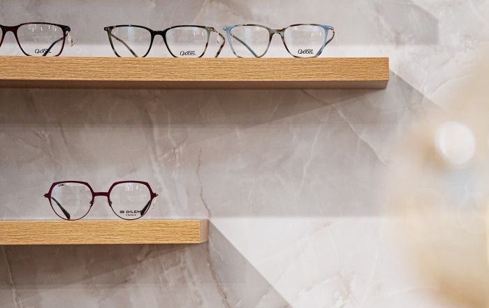 Mehrere moderne Brillen auf Holzregalen